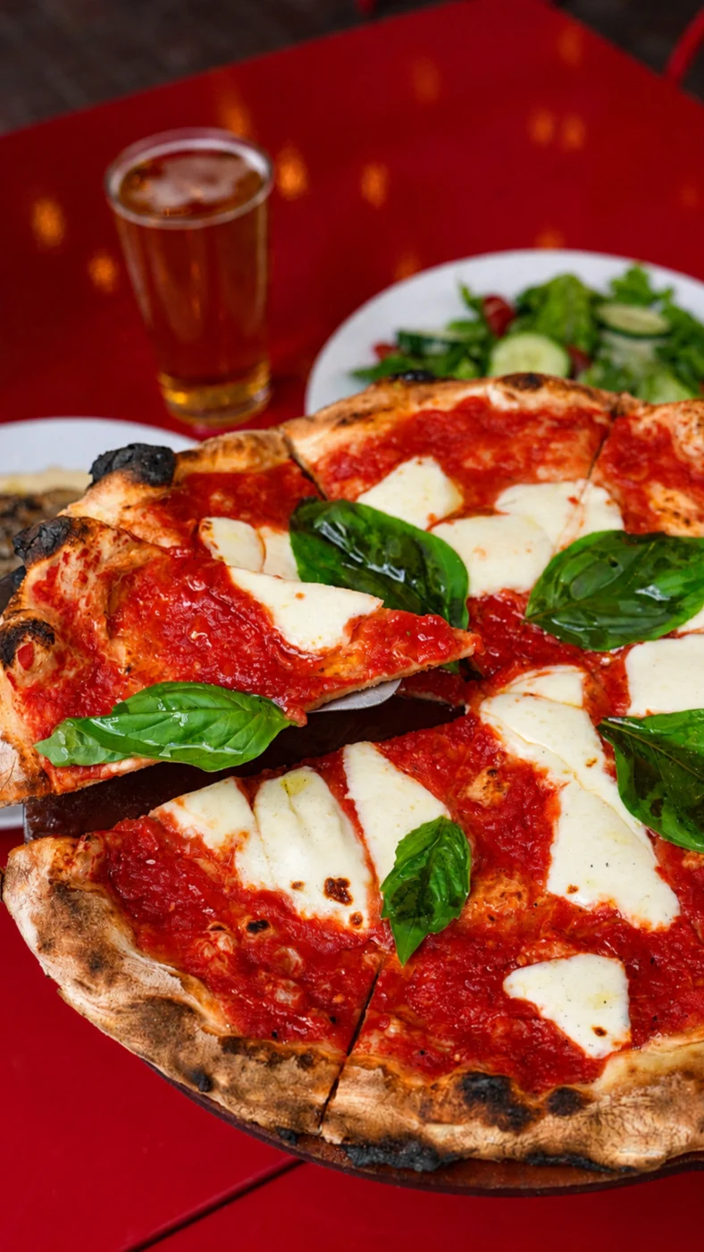 Pizza, basil and mozzarella on a red restaurant table